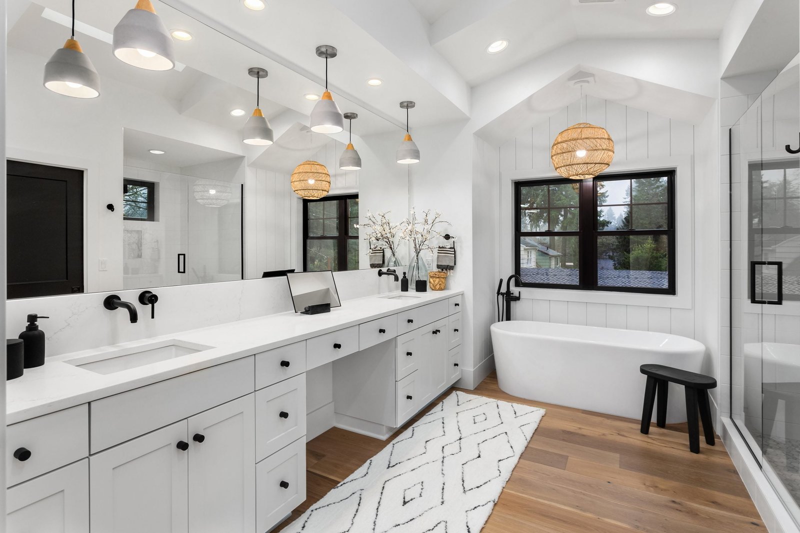 Bathroom in luxury home with double vanity, bathtub, mirror, sin