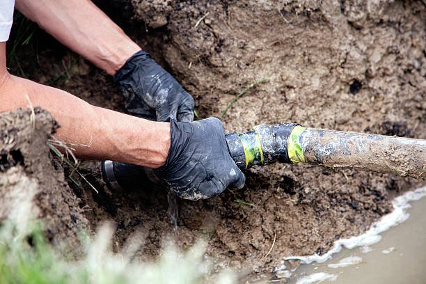 Plumber Repairing a Broken Pipe in a Septic Field